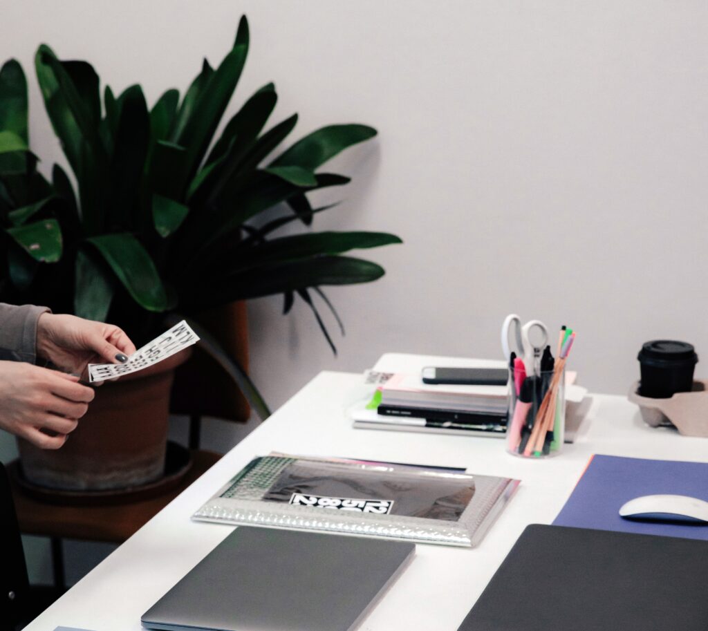 Mesa de diseñadora con sus manos sosteniendo una nota - Servicios de Branding Sostenible